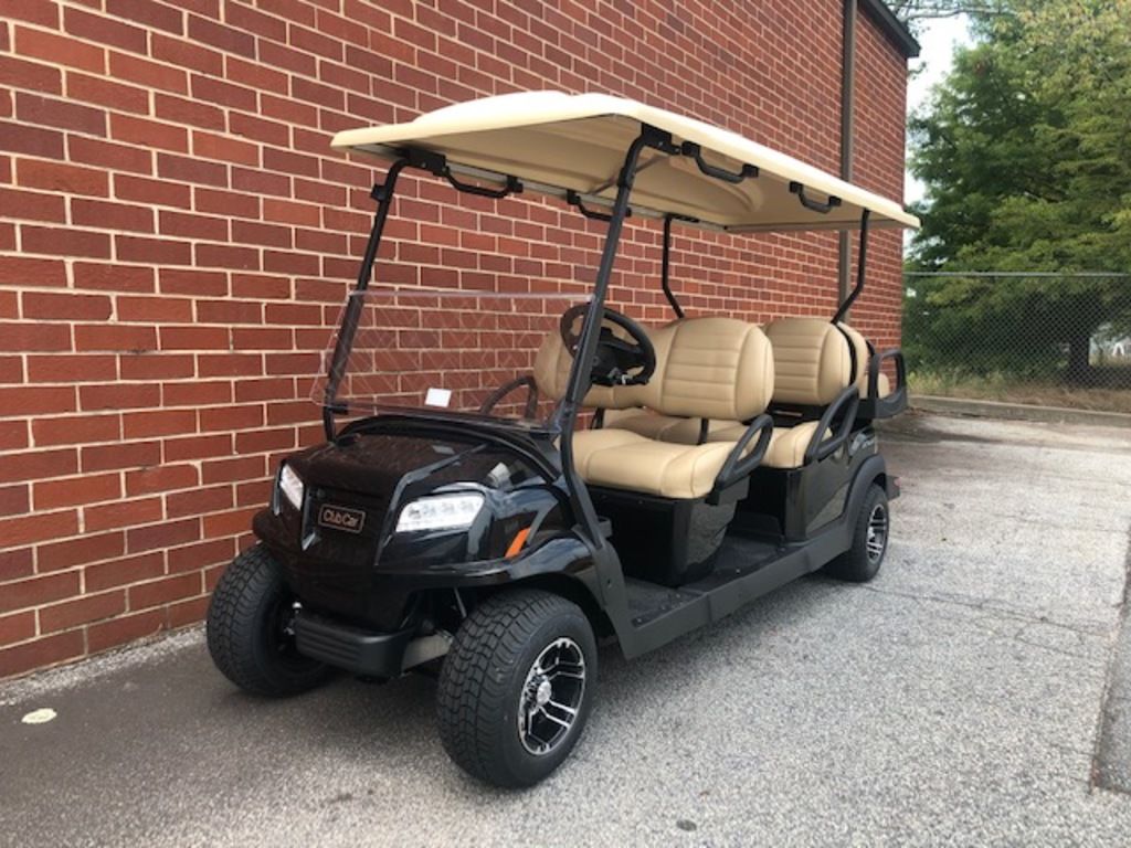 A black 2020 Club Car® Onward® 6 Passenger Golf Cart parked next to a brick wall.