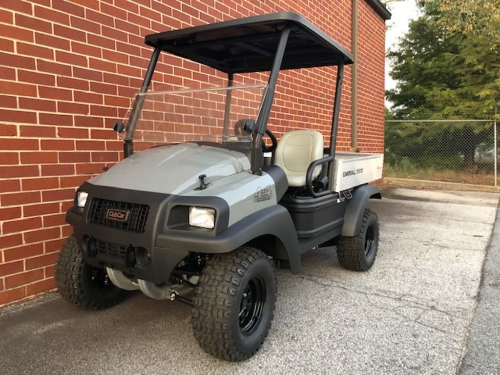 A gray Club Car® UTV in front of a brick building.